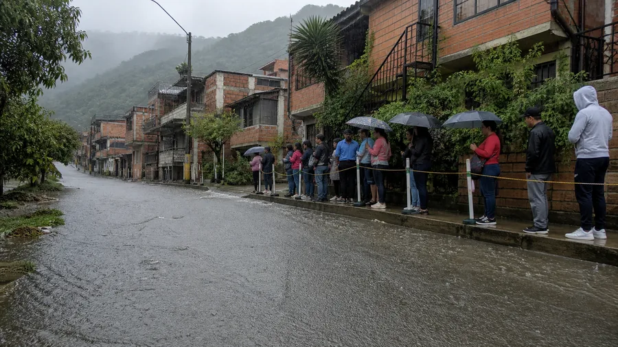 Personas permanecen en un andén elevado detrás de una barrera mientras una vía está cubierta por agua
