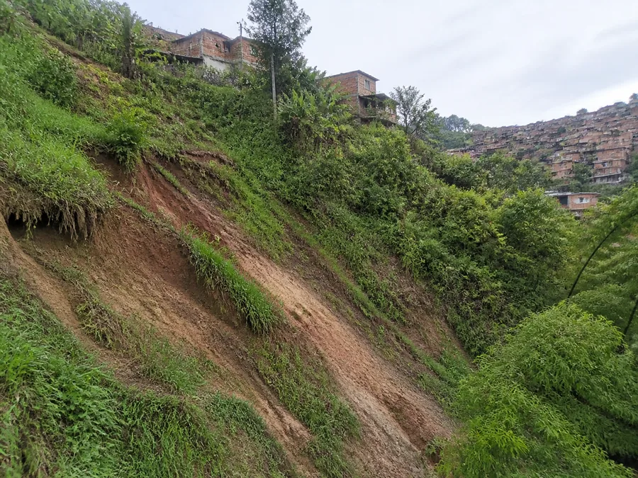 Ladera húmeda con señales tempranas de movimiento del suelo en un barrio de montaña